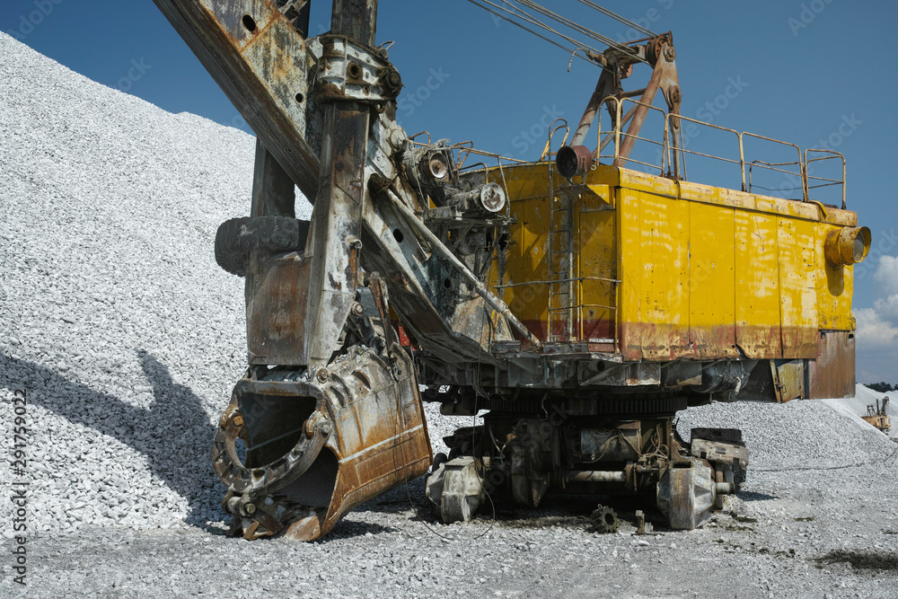 Faulty mine excavator in the background of hills of crushed stone and blue sky, close-up. Heavy equipment. Faulty mine excavator in the background of hills of crushed stone and blue sky, close-up. Heavy equipment.