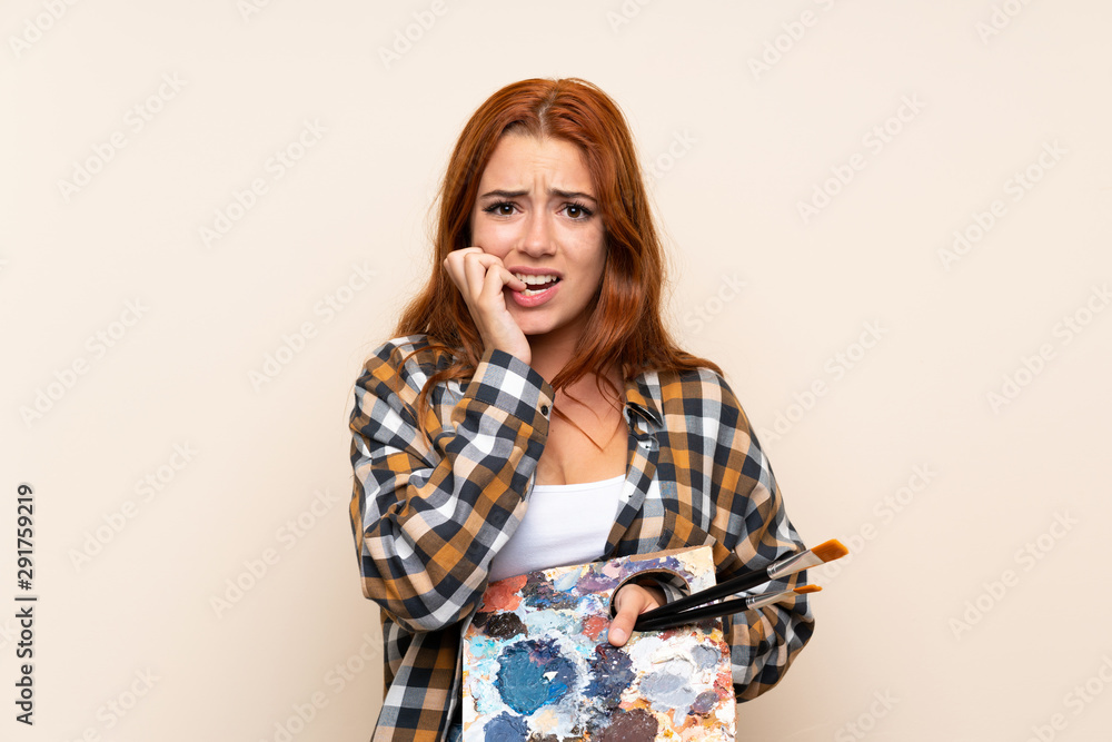 Teenager redhead girl holding a palette over isolated background nervous and scared Teenager redhead girl holding a palette over isolated background nervous and scared