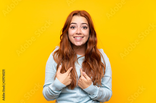 Teenager redhead girl over isolated yellow background with surprise facial expression © luismolinero