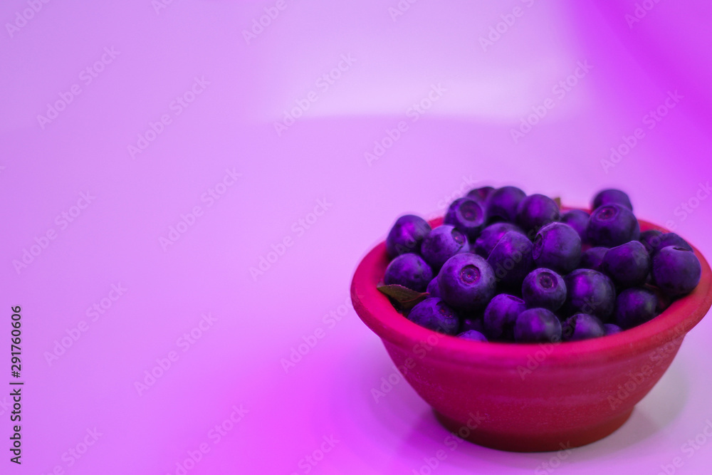 a plate of blueberries with a pink highlighting. space for text a plate of blueberries with a pink highlighting. space for text