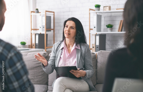 Confident psychologist talking with patients in her consulting room photo