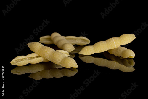 Group of six whole uncooked pasta cavatelli isolated on black glass photo