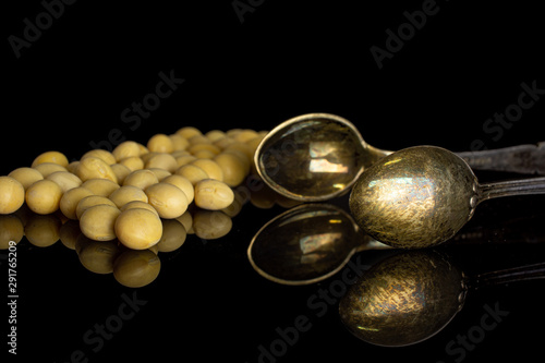 Lot of whole raw yellow soya bean with sugar tongs isolated on black glass