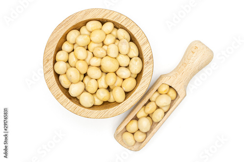 Lot of whole raw yellow soya bean in wooden bowl with wooden spoon flatlay isolated on white background
