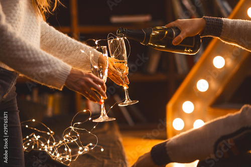 man and woman drink champagne in a cozy room in the evening setting