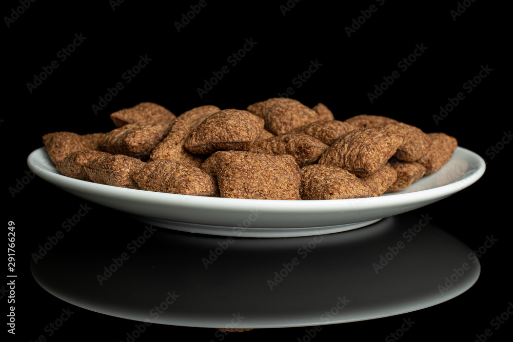 Lot of whole crispy brown cereal pillow on white ceramic plate isolated on black glass Lot of whole crispy brown cereal pillow on white ceramic plate isolated on black glass