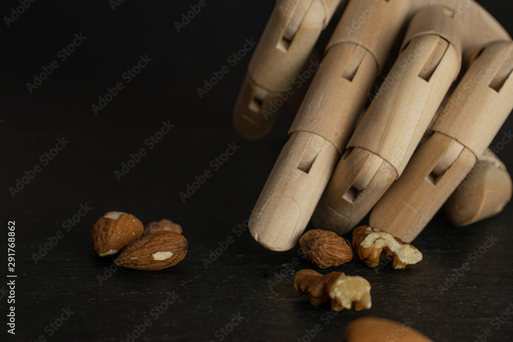Lot of whole brown almond nut heap with wooden arm isolated on grey stone