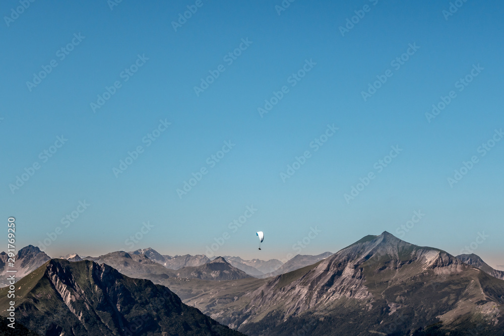 White paraglider flying above Chamonix valley mountains in summer
