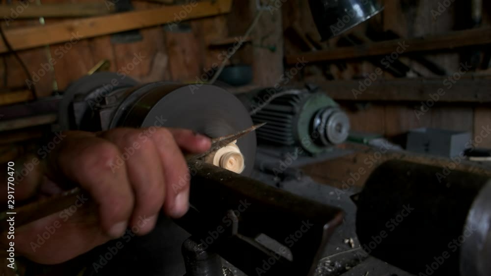 Hands of craftsman working on lathe machine at workshop. Turner is working on the woodworking lathe machine with a knife. Hands of craftsman working on lathe machine at workshop. Turner is working on the woodworking lathe machine with a knife.