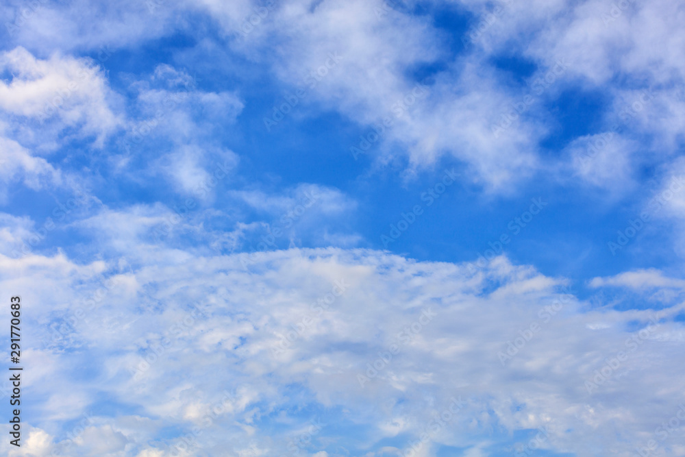 White lush and cheerful clouds float in the bright saturated blue sky.