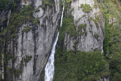 wąskie i wysokie wodospady los amigos w Ushuaia spływające po wysokich stromych ścianach skalnych pokrytych fragmentarycznie roślinnością 