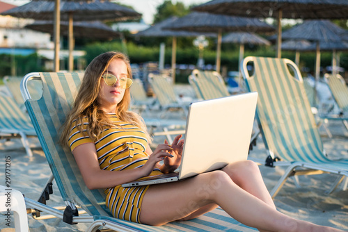 Young woman using laptop computer on a beach. Freelance work concept