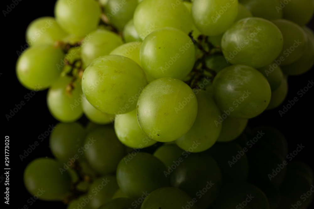 Lot of whole fresh green grape isolated on black glass