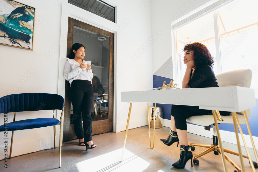 Low angle view of two young businesswomen relaxing and talking Low angle view of two young businesswomen relaxing and talking