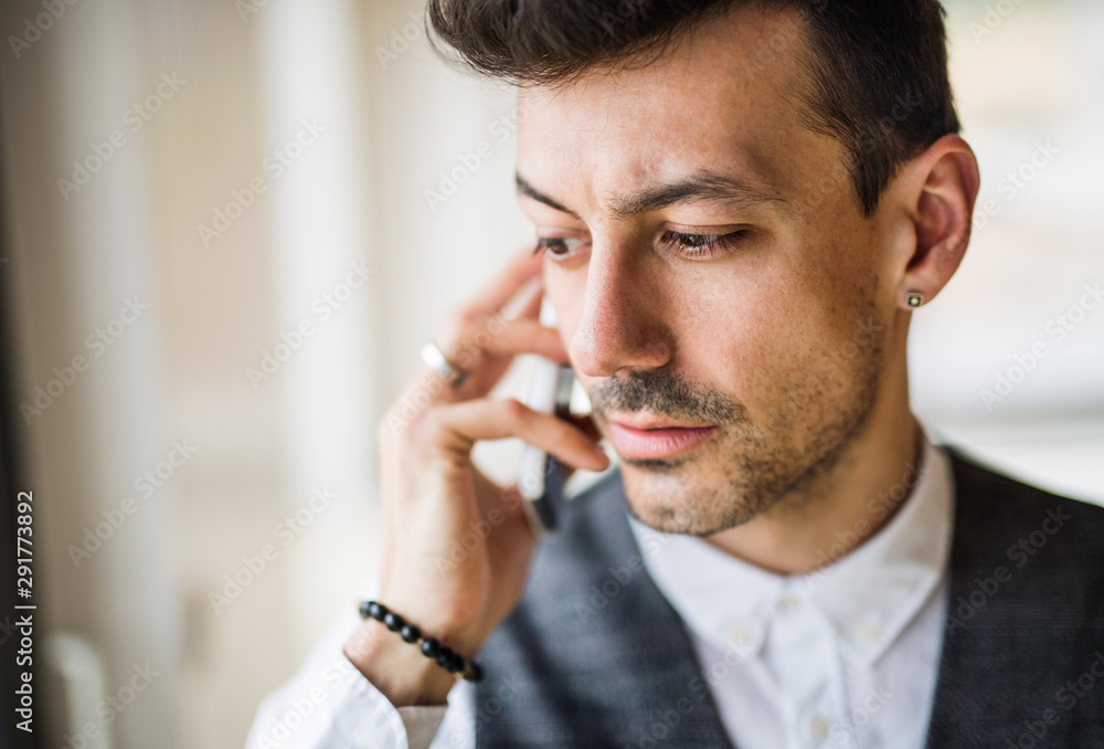 Young man with smartphone standing indoors at home, making a phone call. Young man with smartphone standing indoors at home, making a phone call.