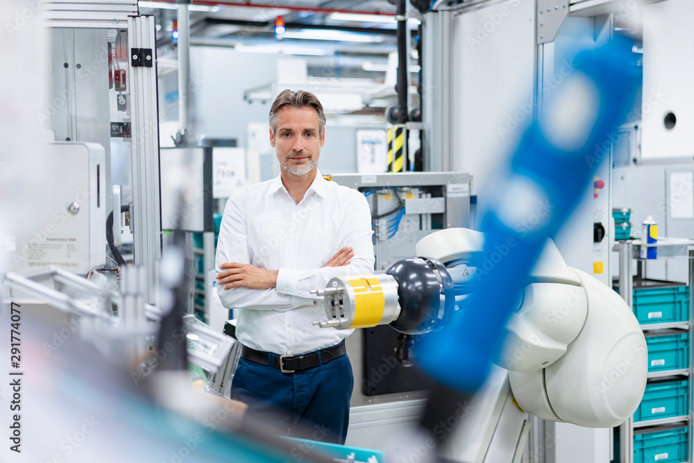 Portrait of confident businessman at assembly robot in a factory Portrait of confident businessman at assembly robot in a factory
