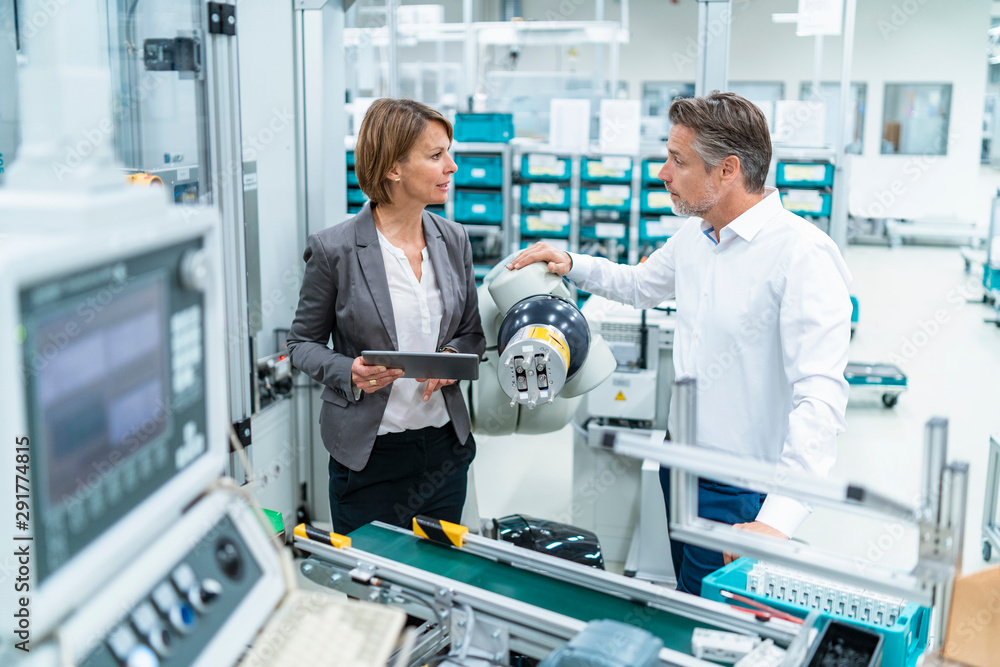 Businesswoman and man talking at assembly robot in a factory Businesswoman and man talking at assembly robot in a factory