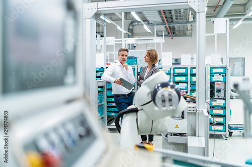 Businesswoman and manwith tablet talking in a modern factory photo