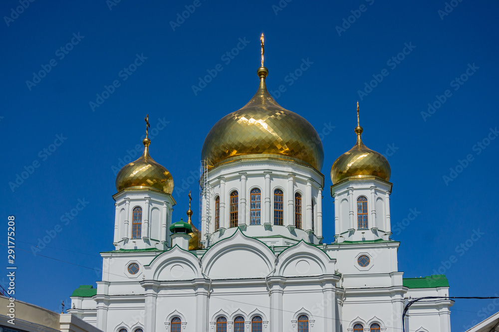 Rostov-on-Don, Russia - September 12, 2019: White Orthodox Cathedral Nativity of Virgin. Golden domes cathedral with snow-white walls against blue sky. Glitter of golden domes with orthodox crosses.