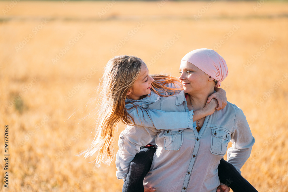 A woman with cancer carrying her daughter on her back, face to face A woman with cancer carrying her daughter on her back, face to face