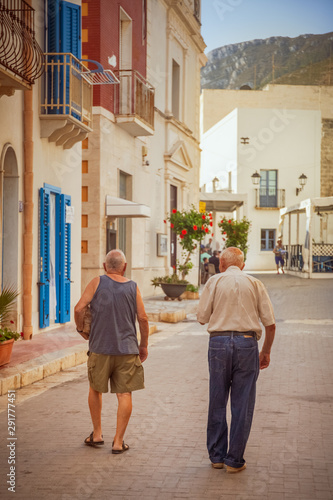Two old men walking in the main street of the village of Marettimo, Egadi islands, Italy