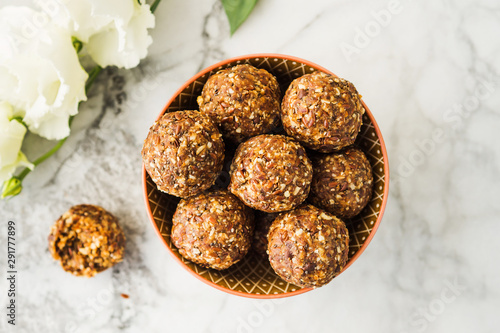 Energy protein balls with healthy ingredients on marble table. Home made with dates, peanut butter, flax and chia seeds, oats, almond and chocolate drops