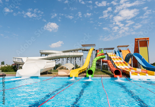 Water park  bright multi-colored slides with a pool. A water park without people on a summer day with a beautiful  cloudy blue sky