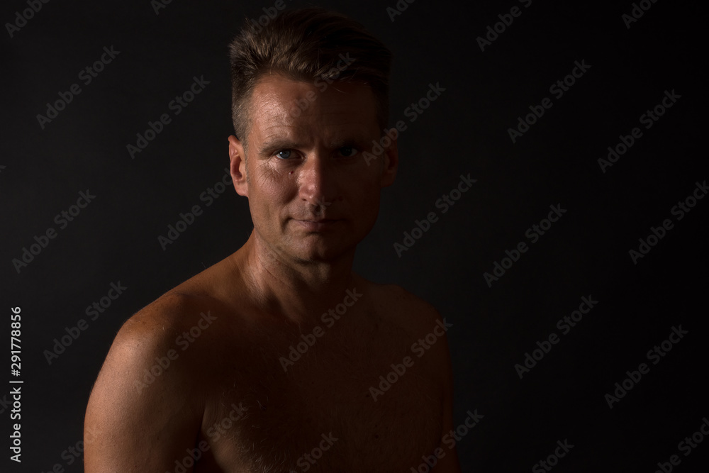Portrait of mature man with naked torso in split light