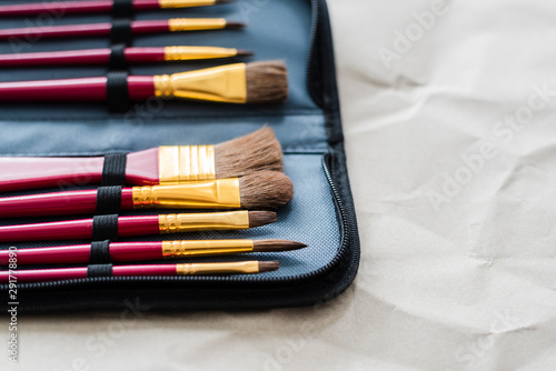 A paint brushes set lays on craft paper.