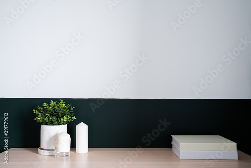 Bedroom working corner and wooden table decorated with white candle in glass and artificial plant in a marble pattern vase on green painted wall/apartment interior detail /copy space / modern style