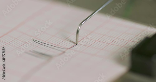 Tight close up footage of the activity of an old fashion lie detector machine in use.