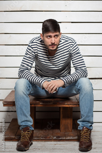 Beautiful man sits on a wooden table
