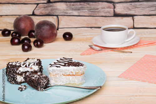 Dark and white chocolate sponge cakes in a shape of hearts. A cup of coffee, peaches, sweet cherries photo