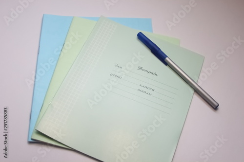  school notebook with pen and paper clips on a white background