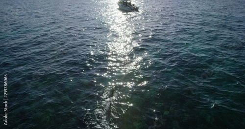 Tilt down aerial, scuba diver swims on ocean surface in slow motion