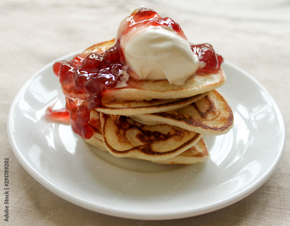 Fresh hot pancakes stack with strawberry jam and sour cream on white plate on natural light linen tablecloth background. Soft focus. Copy space. Pancake carnival maslenitsa breakfast concept Fresh hot pancakes stack with strawberry jam and sour cream on white plate on natural light linen tablecloth background. Soft focus. Copy space. Pancake carnival maslenitsa breakfast concept