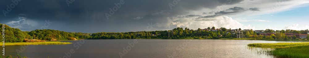 Wide panorama over a lake with power lines going across on the far shore.