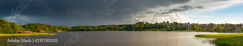 Wide panorama over a lake with power lines going across on the far shore.
