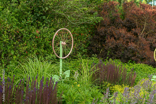 Art installation consisting of a bicycle wheel amonst grass and flowers. photo