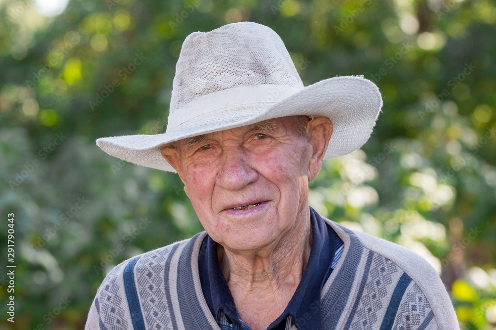 Portrait of an old man in a white hat on a blurred background_