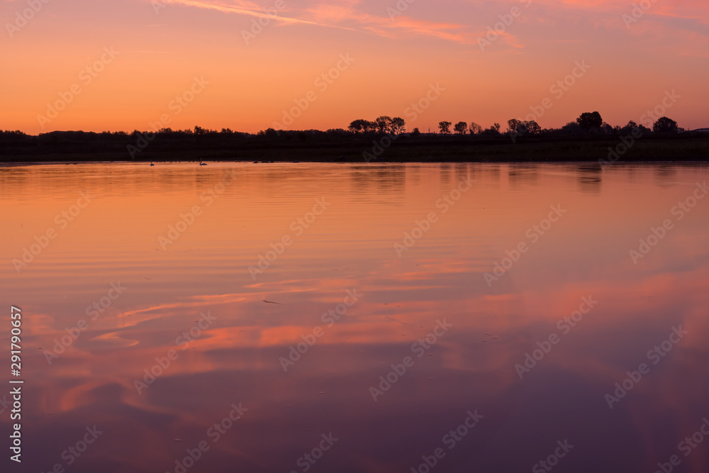 Sunrise at the border of the Netherlands and Belgium. Two countries split by the river Meuse. Picture taken from the belgium side during golden hour with reflection in the water