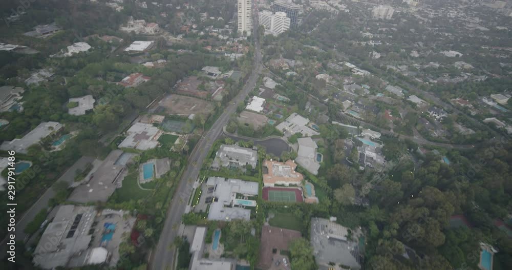 Foggy helicopter aerial moving from suburban area to urban area, day