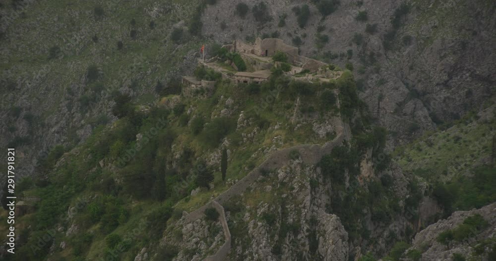 Helicopter aerial zooming away from old castle ruins on top of mountain, surrounded by mountains, foggy day Helicopter aerial zooming away from old castle ruins on top of mountain, surrounded by mountains, foggy day