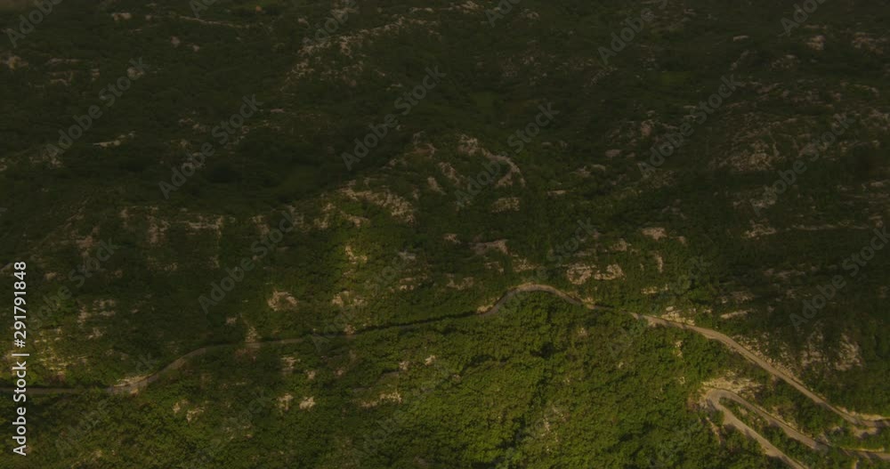 Drone aerial panning over green hilly landscape, sunlight peaking through clouds, day Drone aerial panning over green hilly landscape, sunlight peaking through clouds, day