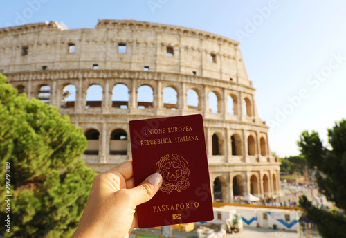 Citizenship concept: hand hold Italian passport in front of Colosseum in Rome. photo