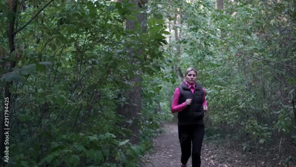 The girl runs in the forest on a cloudy day. Morning running. Healthy lifestyle. The girl runs in the forest on a cloudy day. Morning running. Healthy lifestyle.