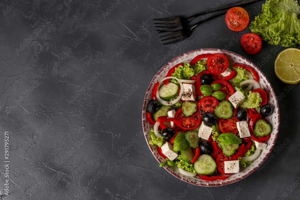 Healthy Greek salad of green lettuce, cherry tomato, onion, pepper, feta cheese, black olives, basil, cucumbers, with olive oil and lemon juice, Copy space, horizontal orientation
