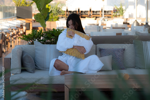 girl holding a pillow sitting on a sofa in a balcony