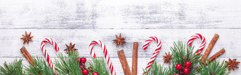 Christmas background. Fir branches, candy cane and gifts on wooden background Horizontal banner Snow effects