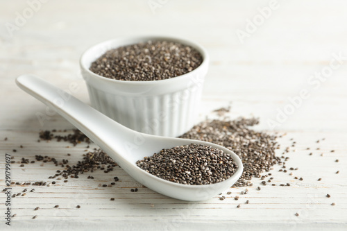 Ceramic sauce boat and spoon with chia on wooden background, close up
